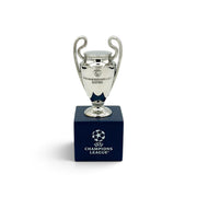 Am Ball UEFA Champions League Pokal-Replika, 70 mm, auf einem eleganten dunkelblauen Holzsockel präsentiert.