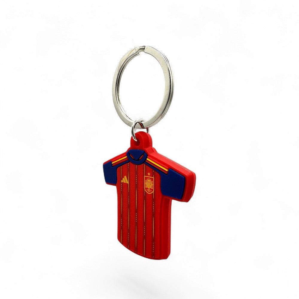 Schlüsselanhänger im Design des Spanien-Trikots (WM 2026) aus rotem PVC mit blauen Ärmeln und gelben Akzenten.