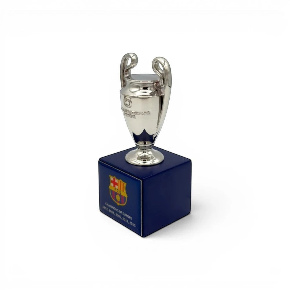 UEFA Champions League Pokal-Replika (70mm) aus Zamak auf blauem Holzsockel mit FC Barcelona-Logo und Titeln.